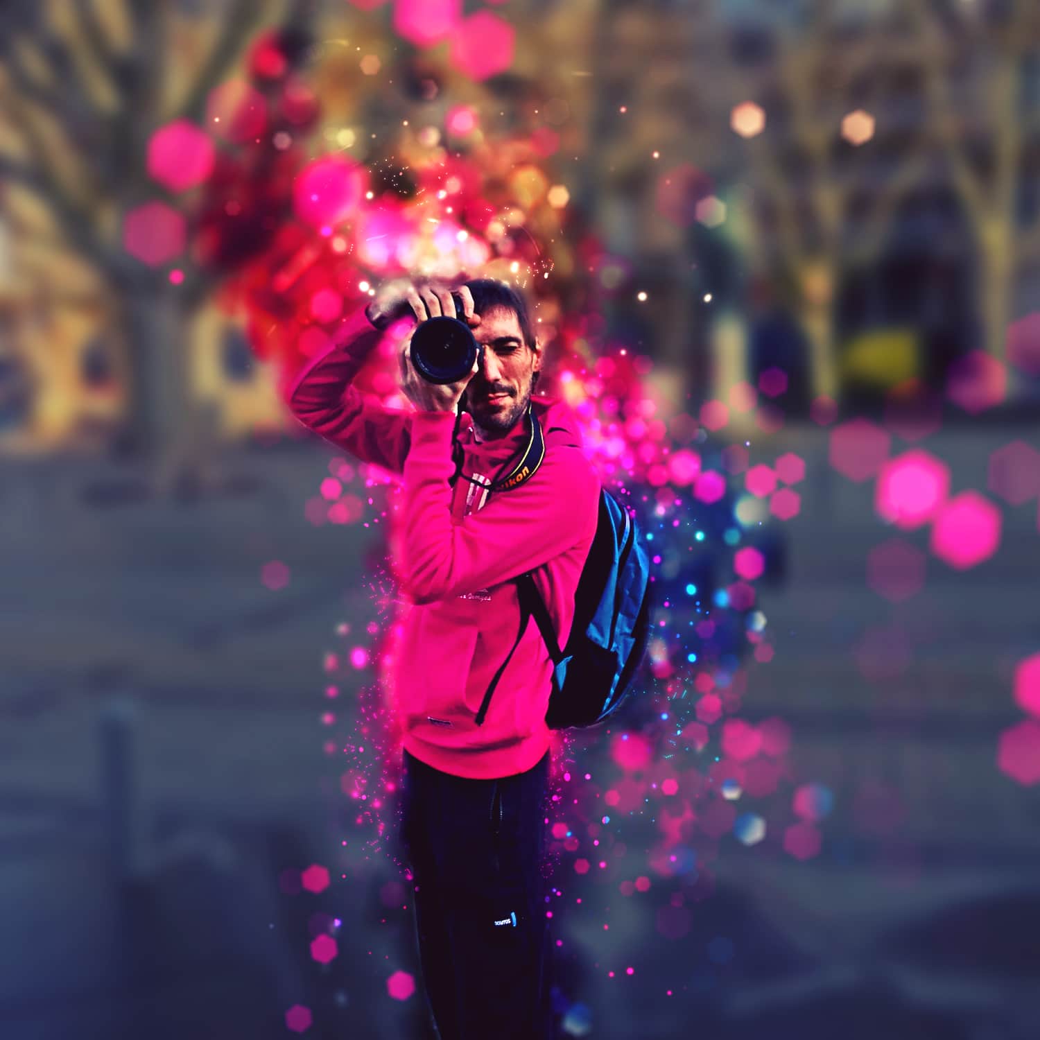 Fotógrafo con sudadera rosa y mochila azul dispara su cámara réflex entre destellos y partículas de luz magenta.