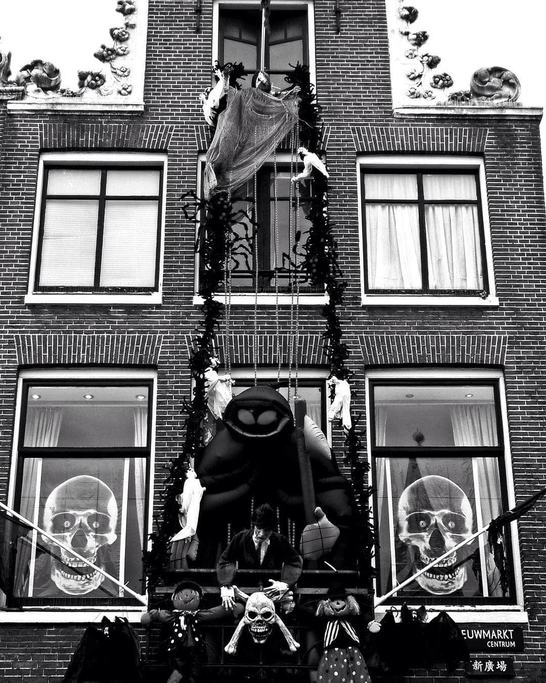 Fachada de una casa de Ámsterdam decorada para Halloween con calaveras y figuras, en blanco y negro.
