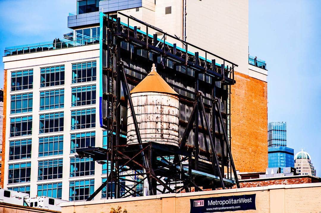 Depósito de agua de madera sobre una estructura metálica, entre edificios de Nueva York.