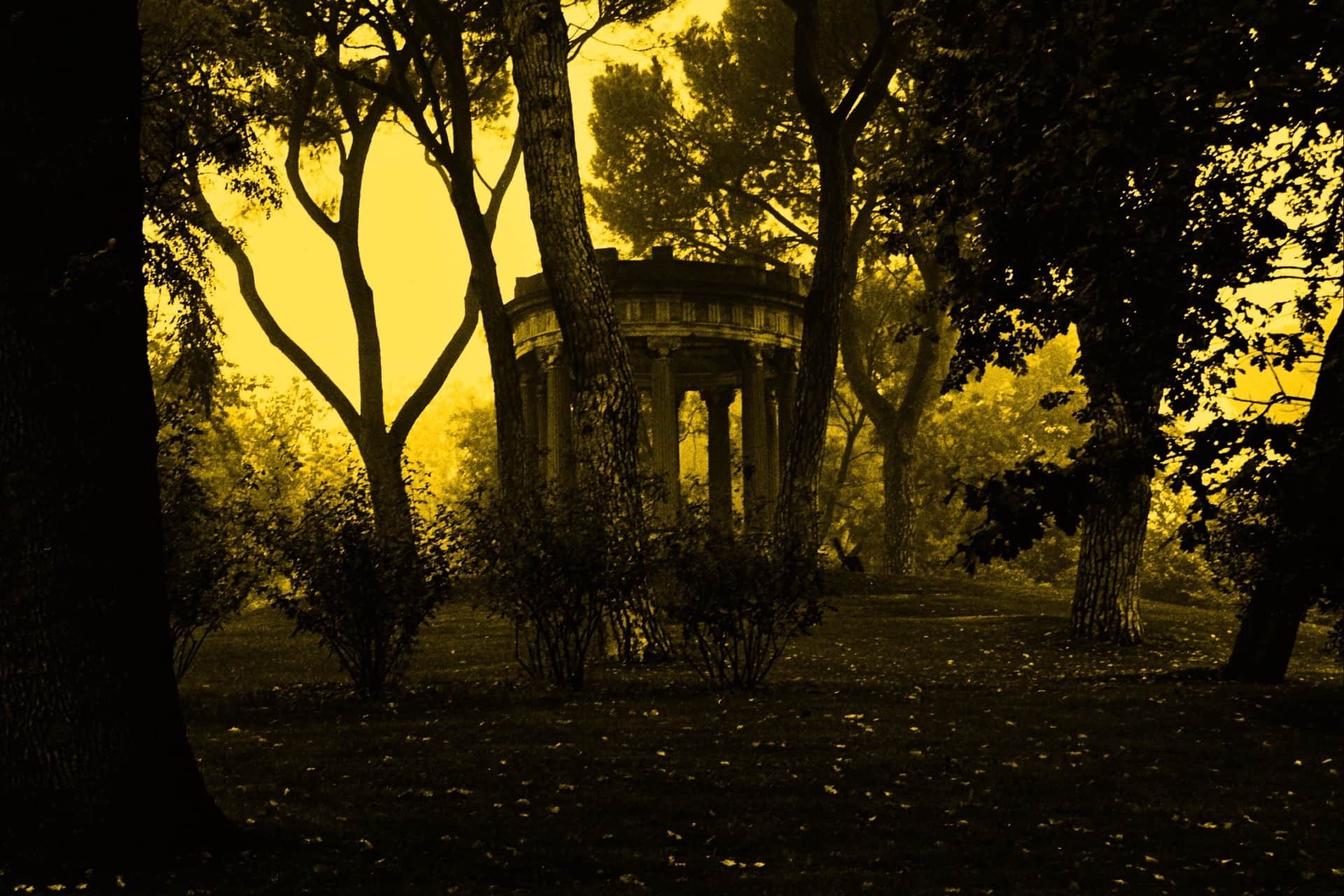 Templete circular con columnas entre los árboles de un parque, en un virado amarillo intenso con la vegetación en sombra.