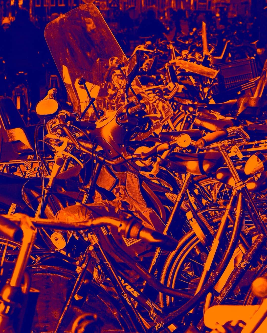 Montón de chatarra y bicicletas amontonadas, con la imagen virada a naranja sobre azul.