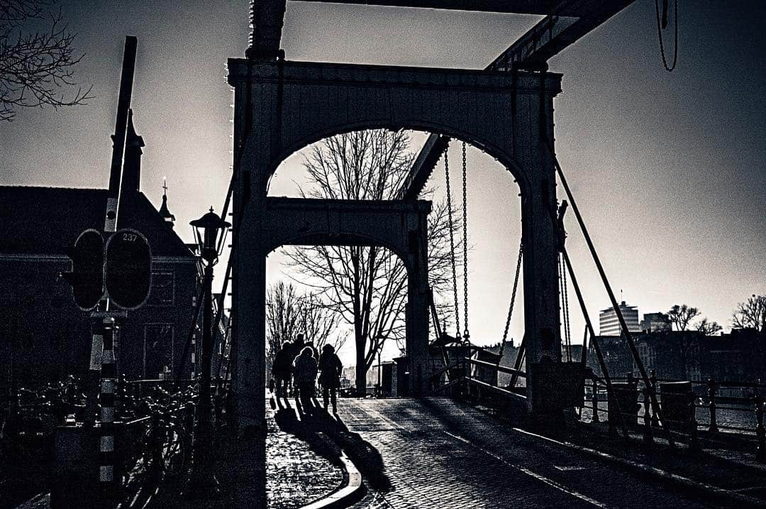 Puente levadizo de hierro visto desde la calzada, en blanco y negro y con el cielo muy oscuro.