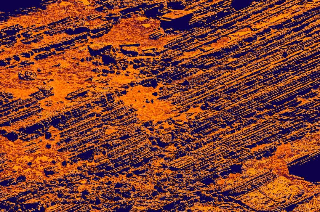 Textura de trazos diagonales llevada a naranja intenso sobre azul, casi abstracta.