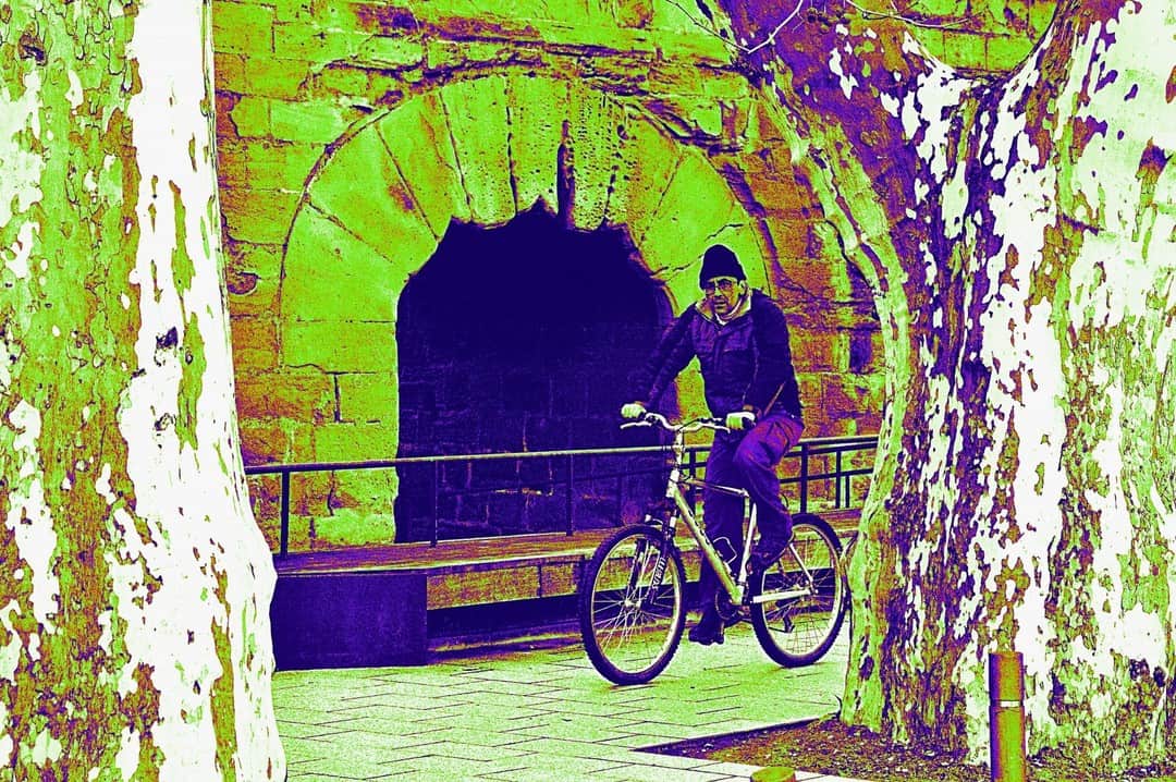 Ciclista bajo un túnel abovedado, con la imagen virada a verde y violeta.