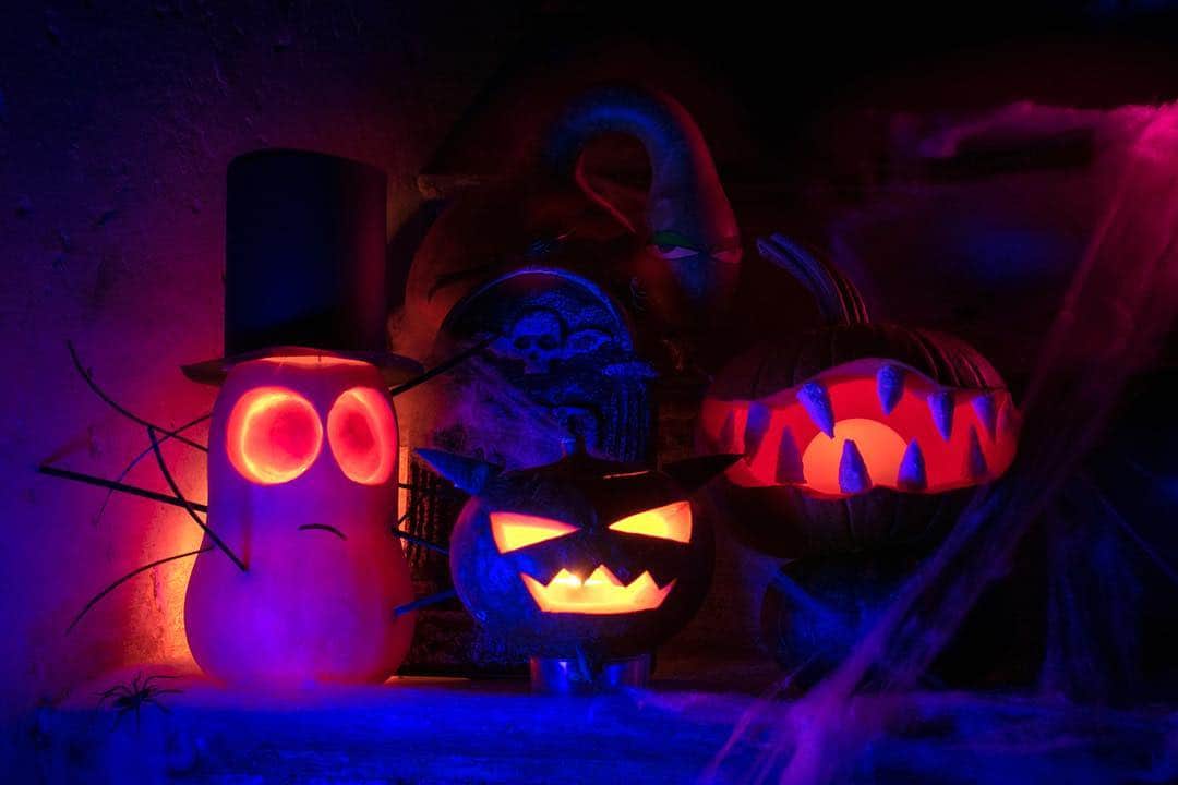 Calabazas de Halloween iluminadas por dentro, con luces rojas y azules sobre fondo oscuro.