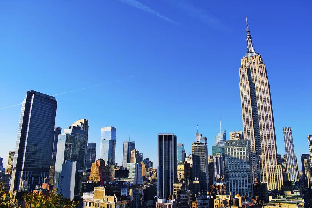 Vista de Manhattan desde una azotea, con el Empire State destacando bajo un cielo azul.