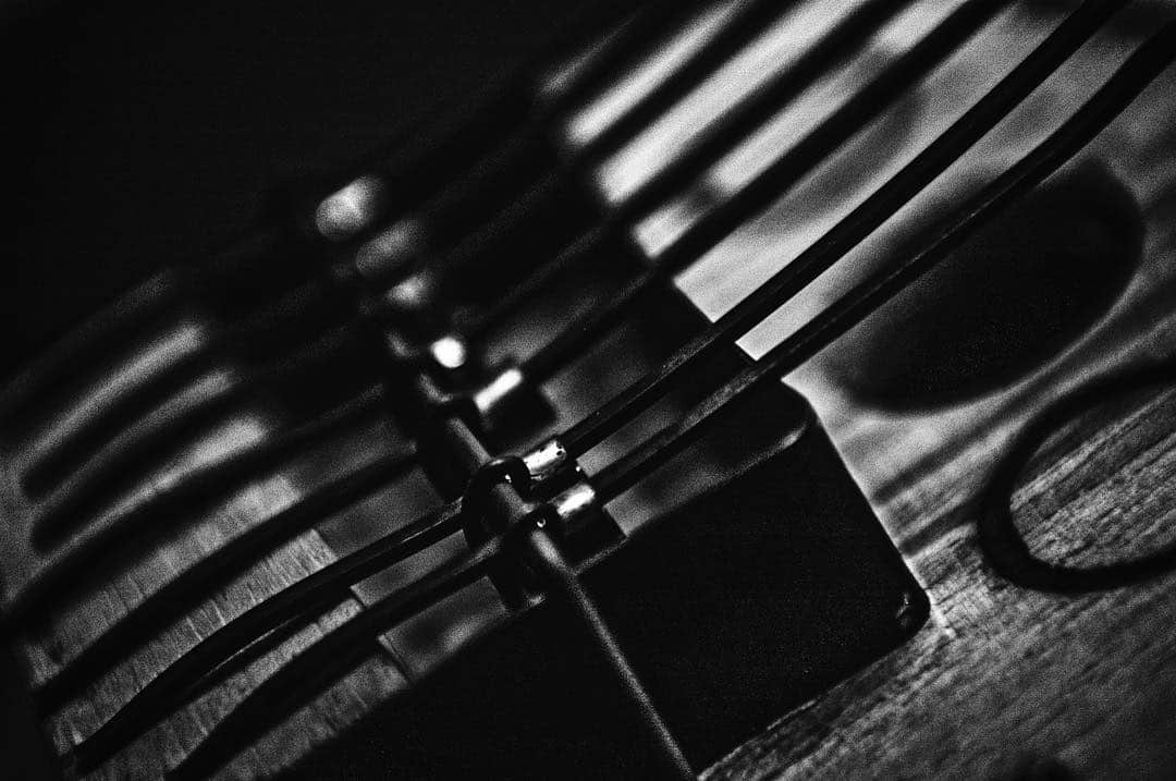 Detalle en blanco y negro de unas tijeras y un tenedor sobre una mesa de madera, muy desenfocado.