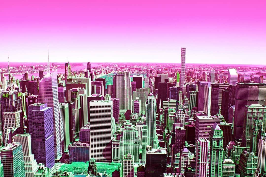 Skyline de Nueva York con los edificios virados a verde y rosa bajo un cielo magenta.