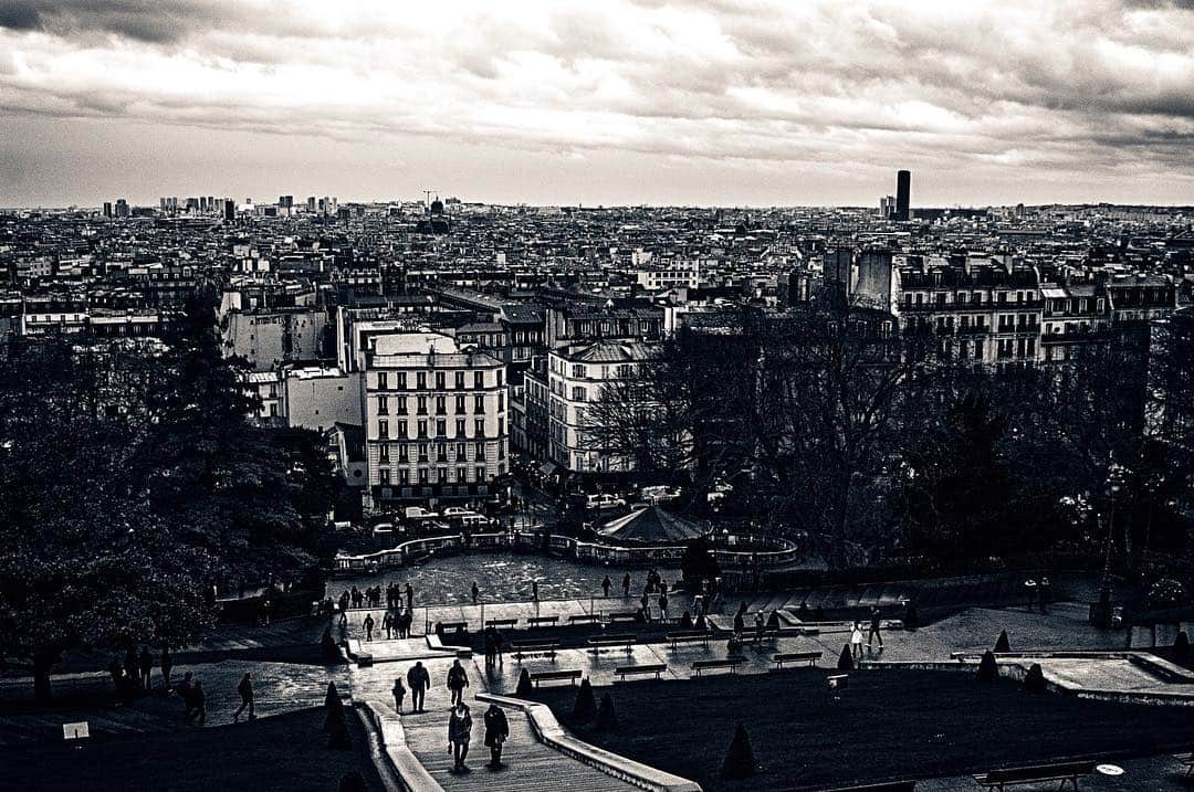 Vista panorámica de París en blanco y negro desde un mirador, con los tejados extendiéndose hasta el horizonte.