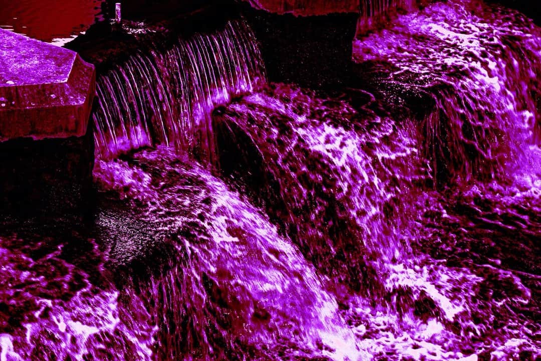 Cascada de agua entre rocas, con toda la imagen virada a magenta y violeta.