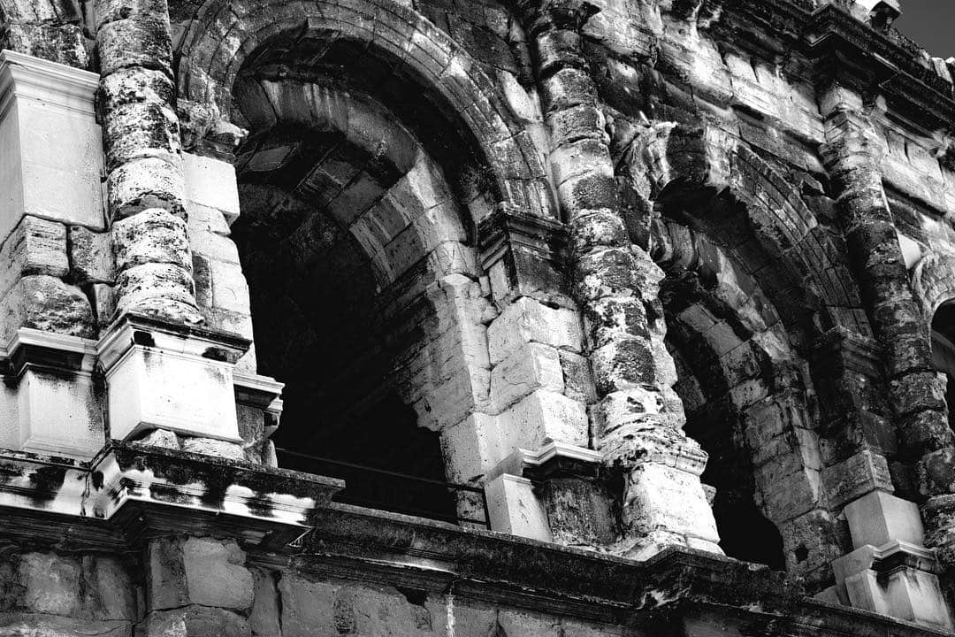 Arcos y columnas de un anfiteatro romano, en blanco y negro.