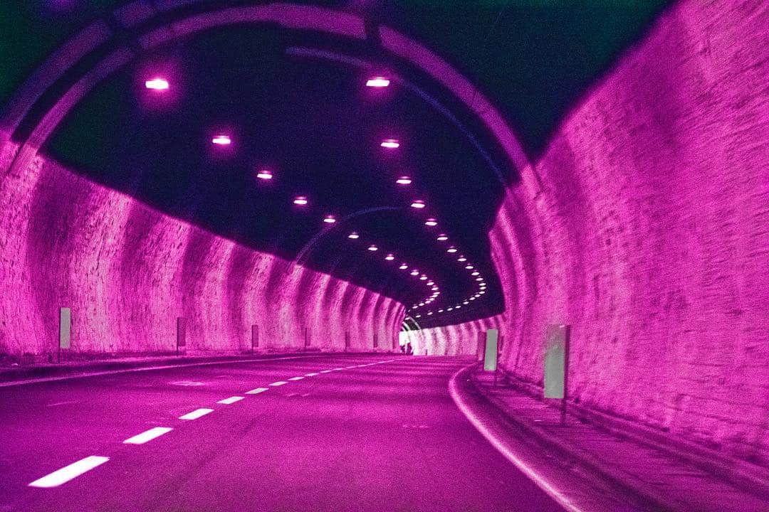 Interior de un túnel de carretera con la bóveda iluminada, virado a magenta intenso.