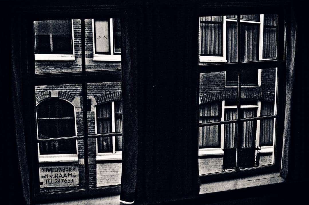 Fachadas de casas de Ámsterdam reflejadas en el cristal de una ventana, en blanco y negro y con líneas muy marcadas.