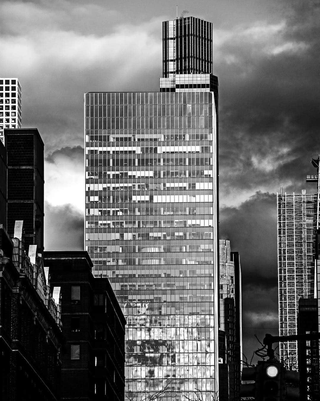 Rascacielos en obras bajo un cielo tormentoso, en blanco y negro y con mucho contraste.