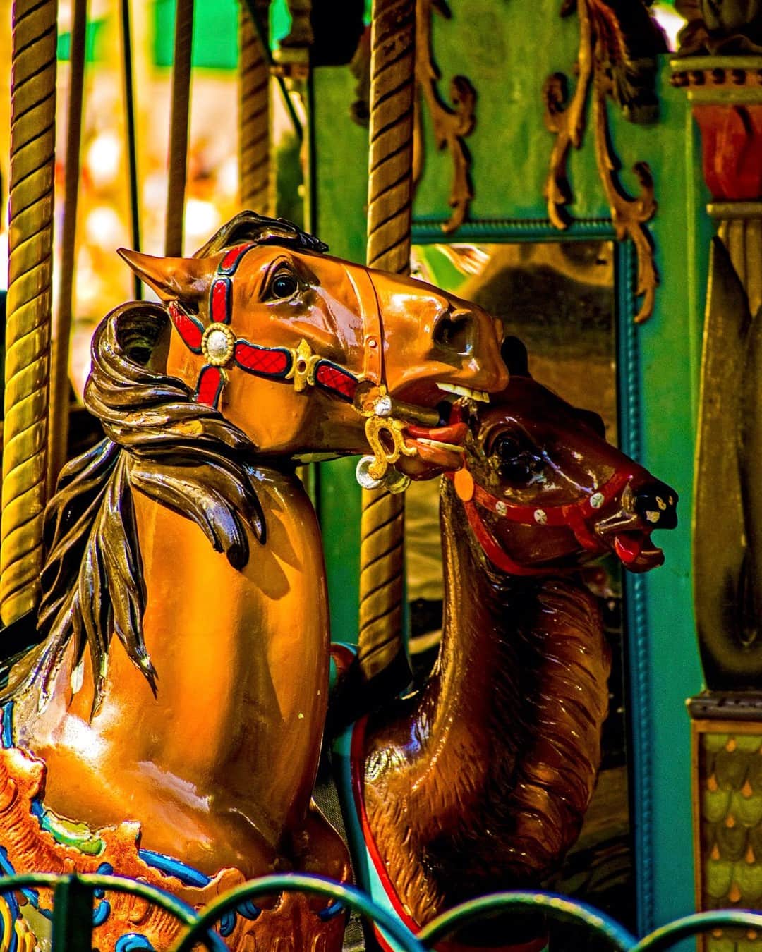 Caballos de madera de un carrusel vistos de cerca, con los arreos pintados y el color muy saturado.