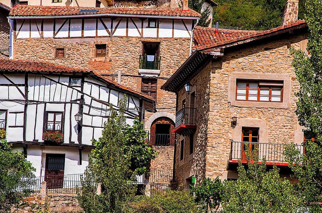 Casas de un pueblo con entramado de madera y ladrillo visto, con balcones y vegetación alrededor.