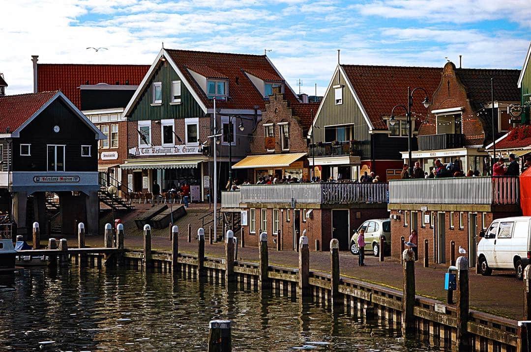 Frente marítimo de Volendam, con casas de madera de colores alineadas junto al agua y una empalizada en primer plano.