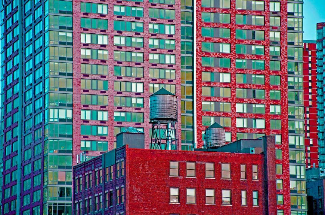 Bloques de viviendas de Nueva York con un depósito de agua en la azotea, con los colores llevados a turquesa, rojo y violeta.