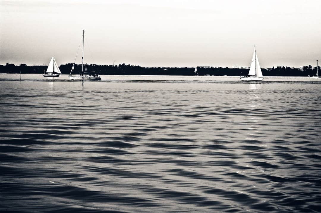 Superficie del mar con dos veleros a lo lejos, en tonos casi monocromos.