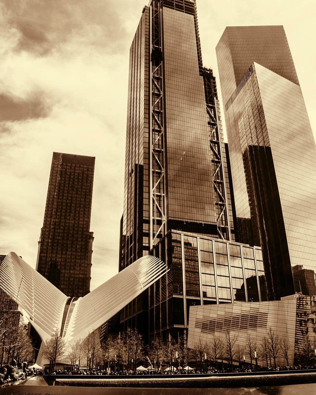 Rascacielos del World Trade Center vistos desde abajo, con las aletas blancas del Oculus al pie, en tonos sepia.